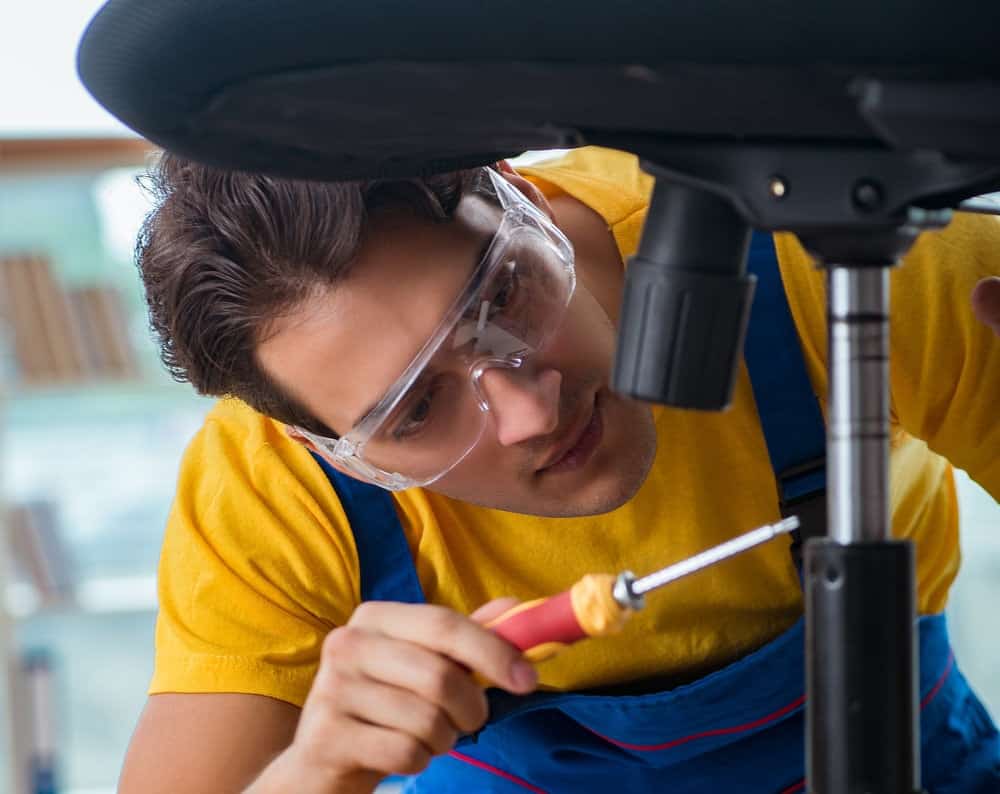 a young technician remove gas lift from a black office chair