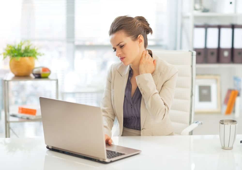 businesswoman sitting at desk suffering from neck pain
