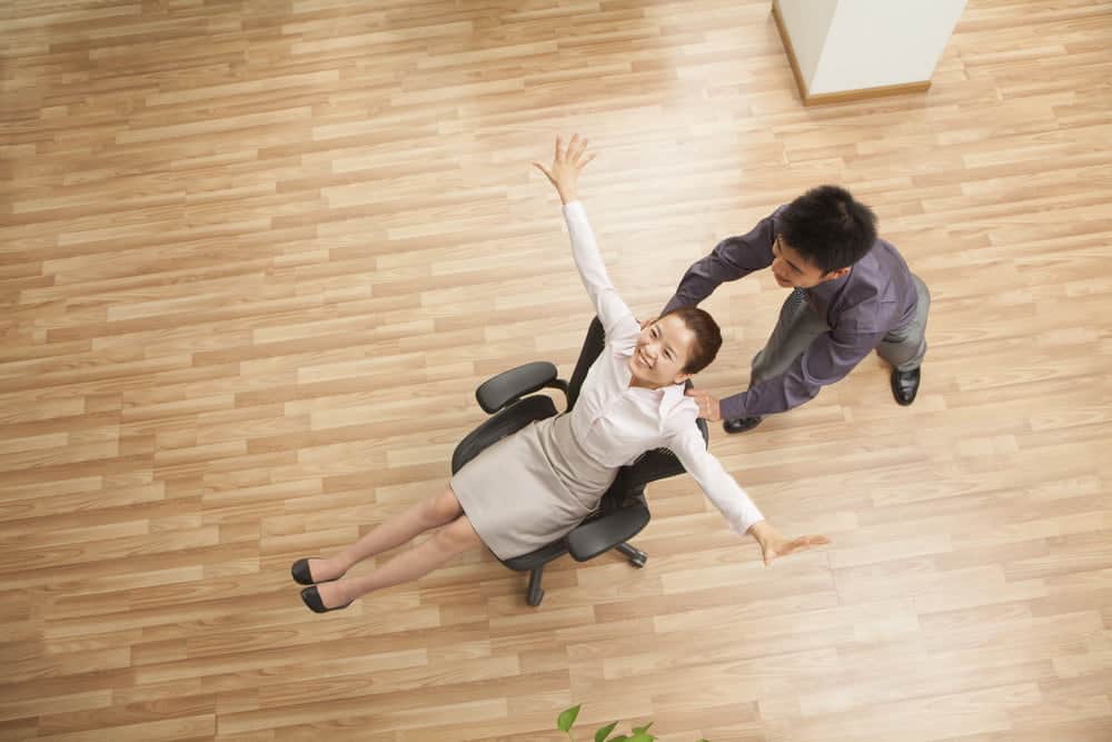 man push woman in office chair on the hardwood floor