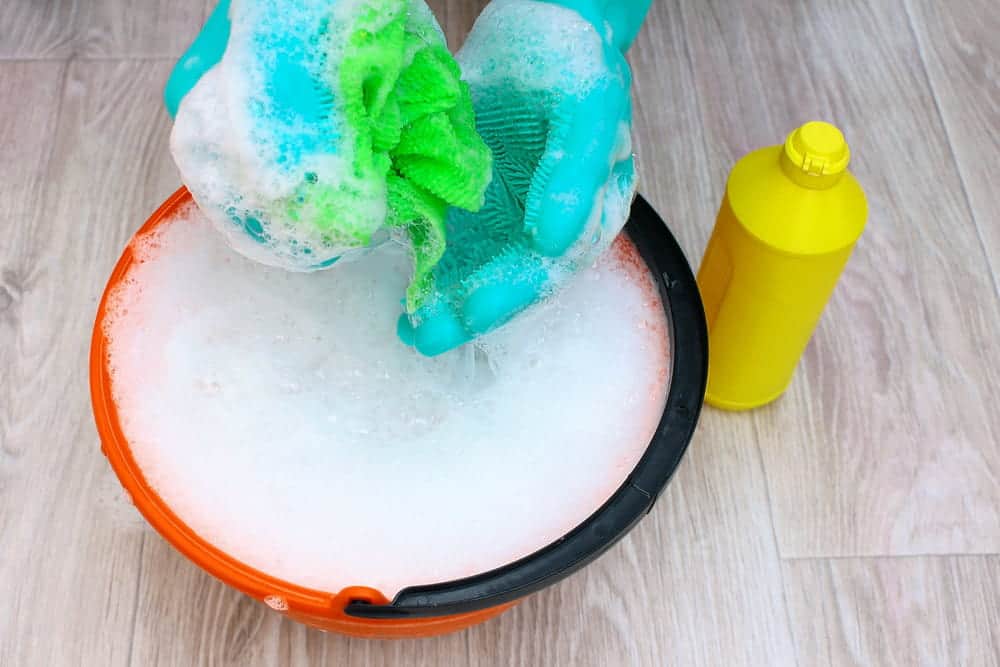 a green cloth and a bucket of foamy soapy water and detergent