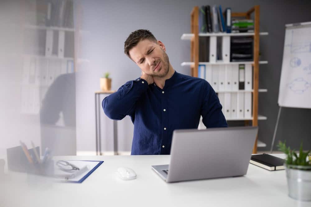 businessman in office chair suffering from neck pain