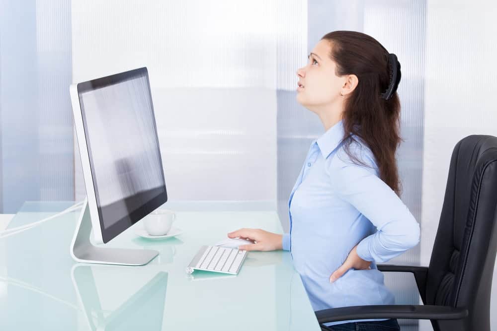 Businesswoman sitting long hours in office chair having back pain