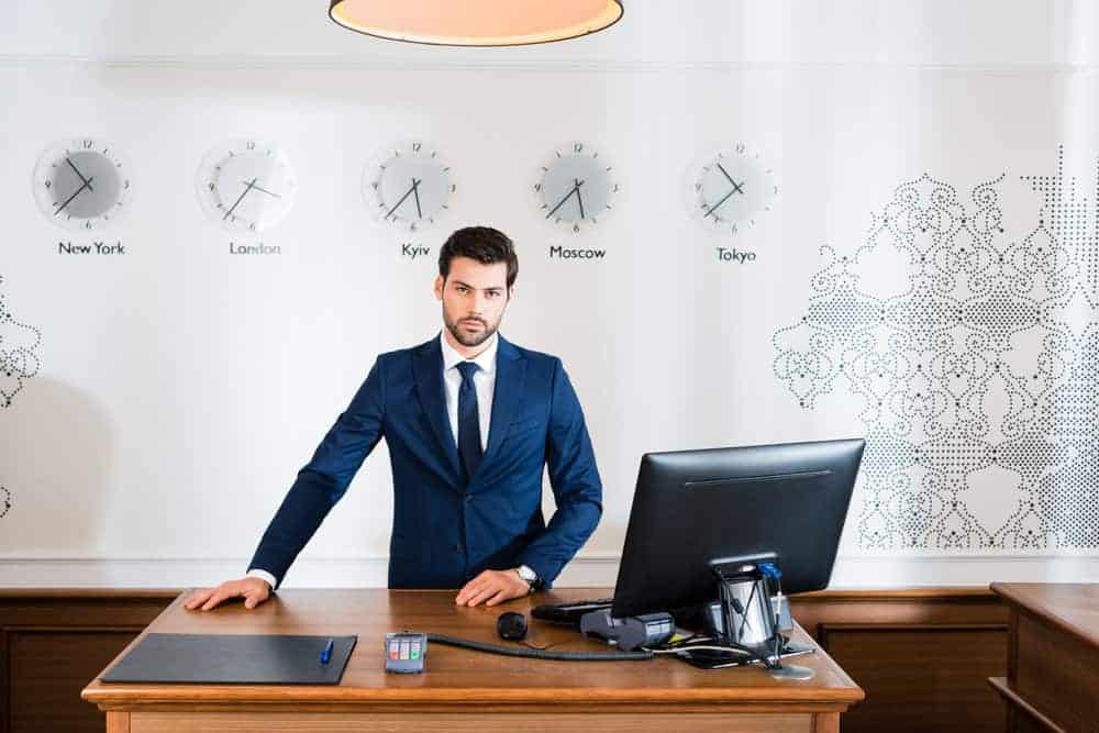 Handsome receptionist standing at reception desk