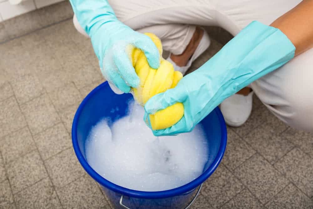 woman squeezing soapy cloth to clean leather office chair