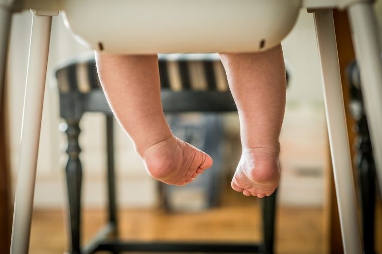 Baby legs dangling in the air while sitting on chair