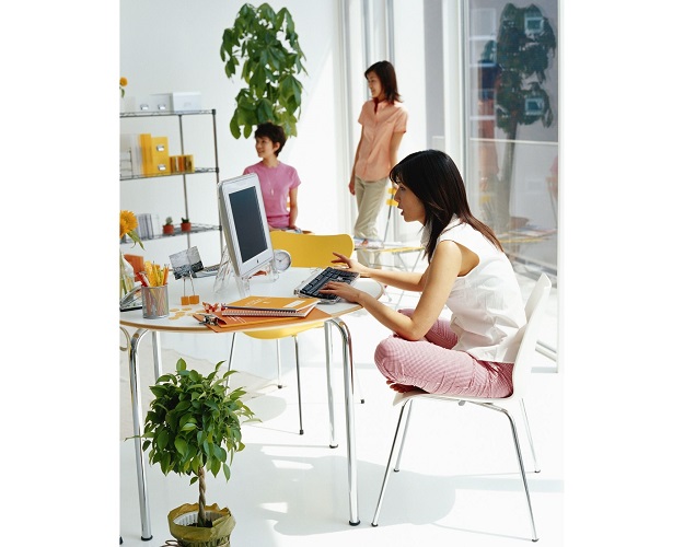 Girl sitting with crossed legs on chair using laptop