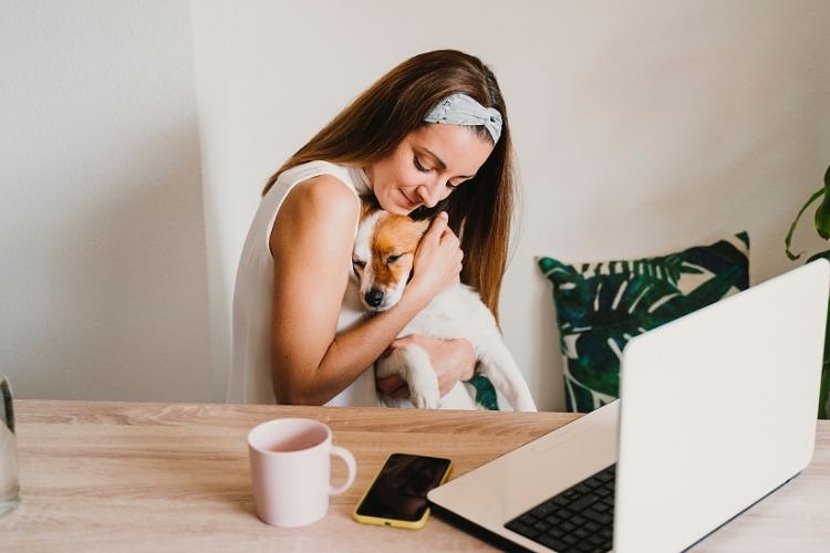 Woman cuddle her dog at her working desk