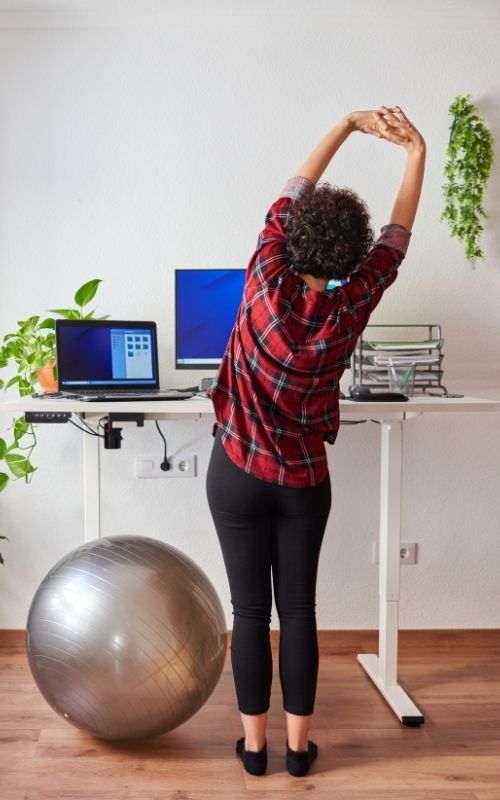 Woman do light exercise while working at standing desk