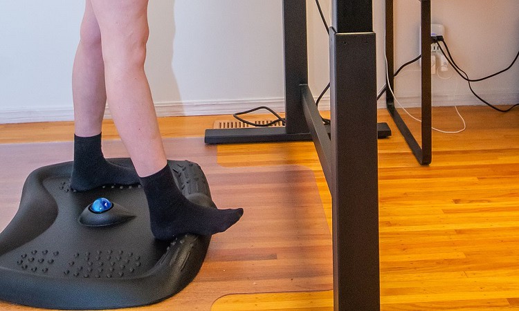 Woman legs standing on mat while using standing desk