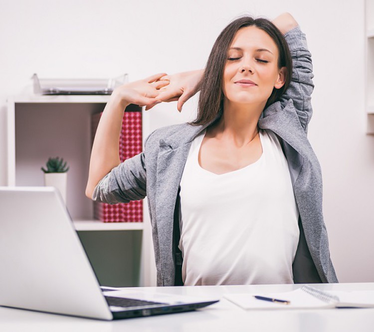 woman stretching at office desk