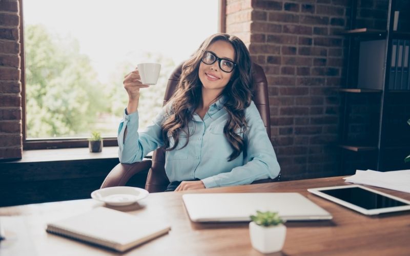 Business woman sitting comfortably in office chair drinking tea