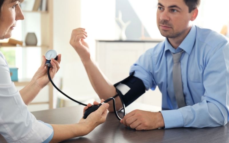 Doctor measuring business man blood pressure