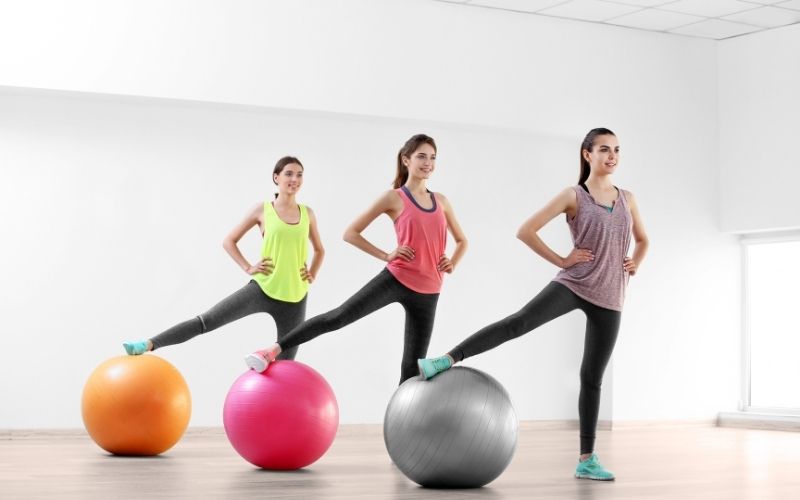 Girls workout with exercise balls in fitness room