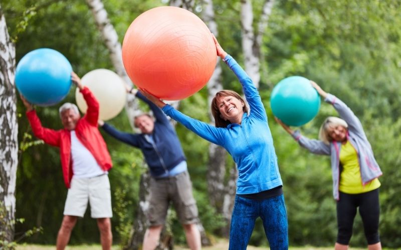 Group of people workout with exercise balls in the park