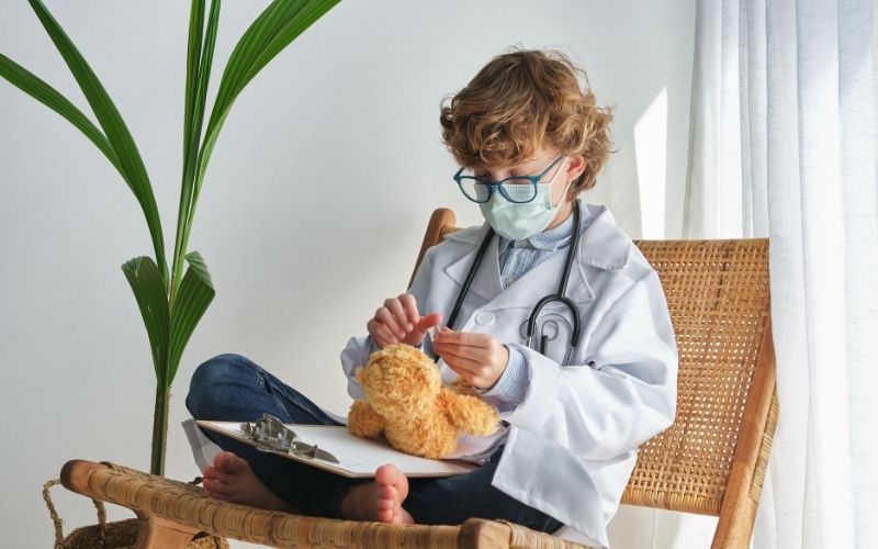 Kid sitting crossed legs on chair and playing with toys