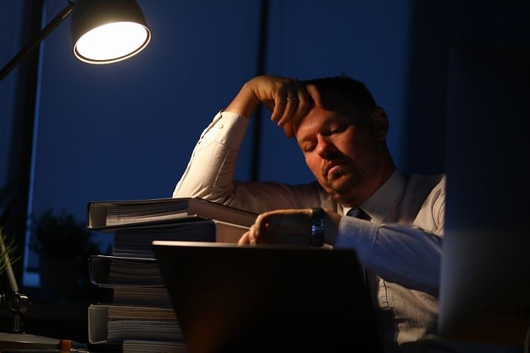 Man sits in office with tired look