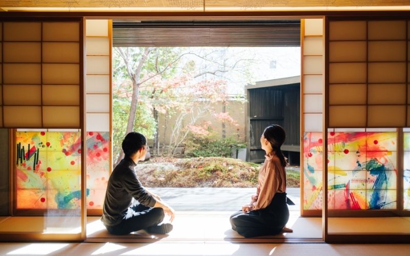 Man sitting with crossed legs and woman sitting in seiza style on tatami mat