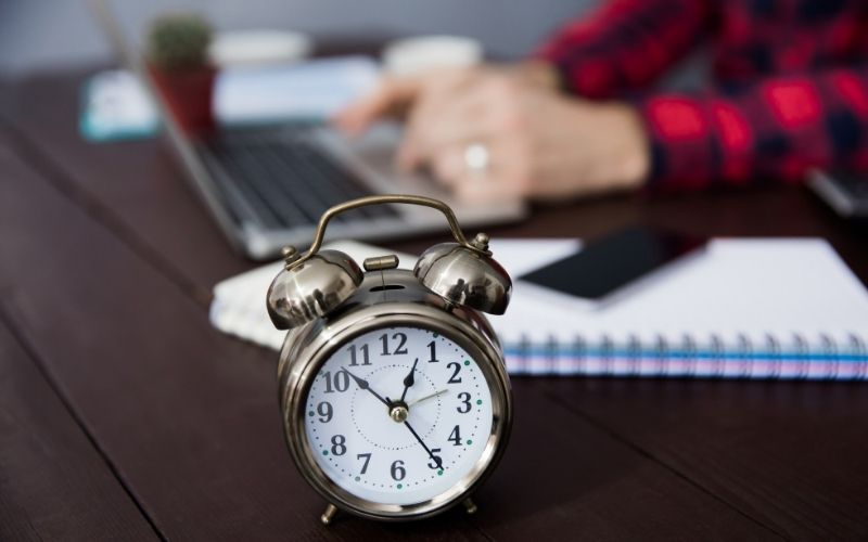 Man working with laptop and a clock on standing desk