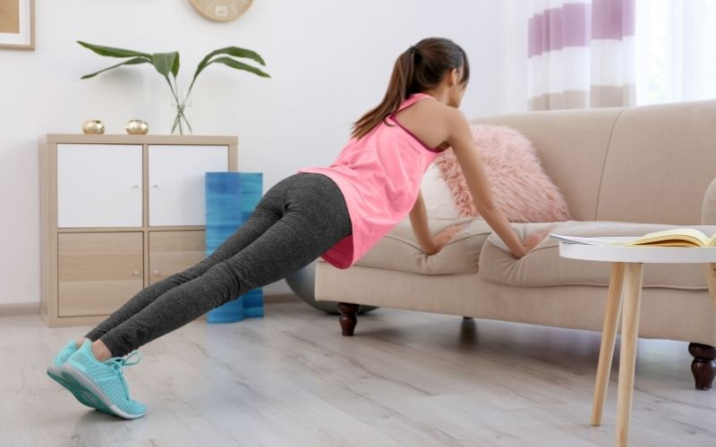 Woman exercises at home with a couch