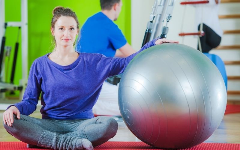 Woman sitting beside an exercise ball