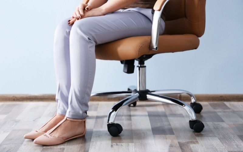 Woman sitting on office chair with legs on the ground