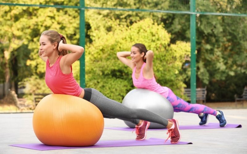 Women exercising with exercise balls outside