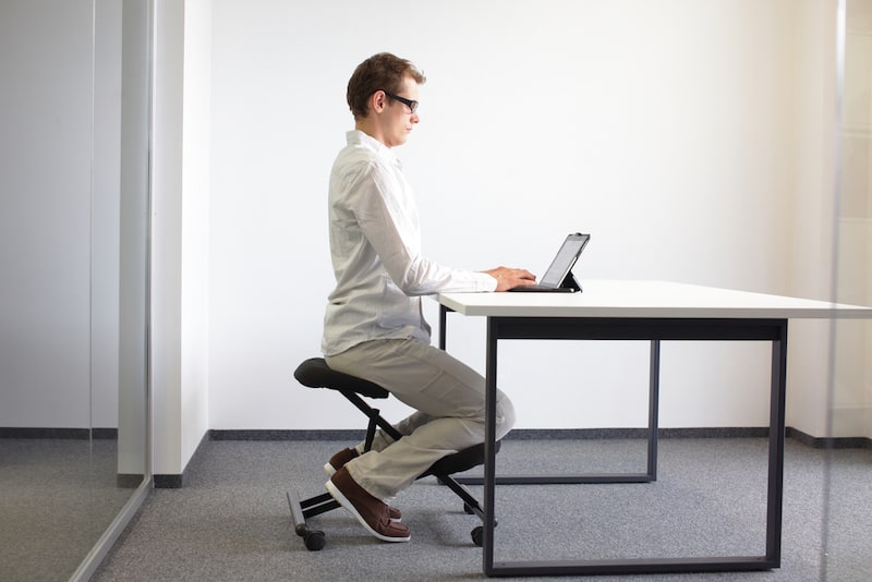 a man is sitting straight on a stool to work
