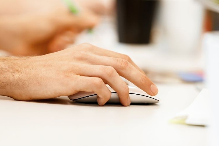 Hand holding a computer mouse on office table