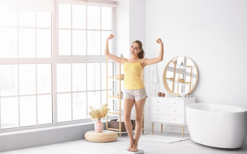 Healthy woman measuring her weight at home