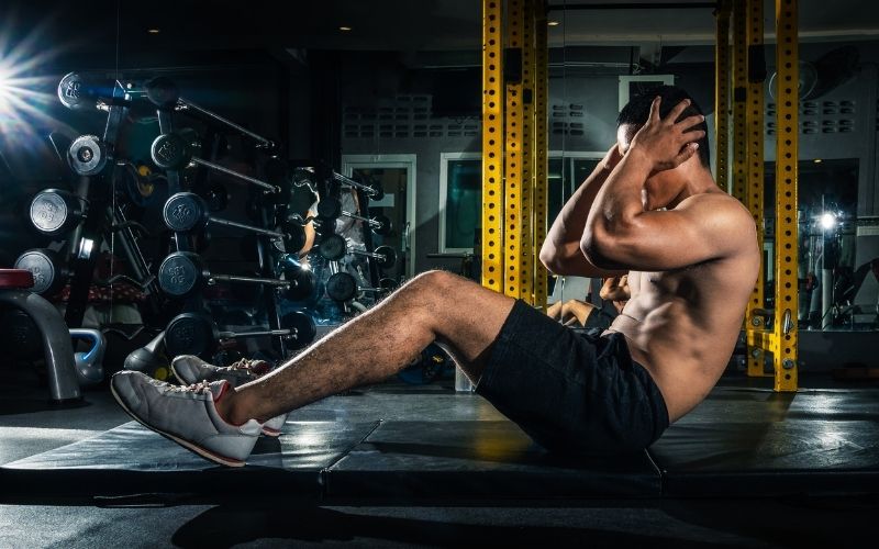 Muscular guy doing crunches at gym