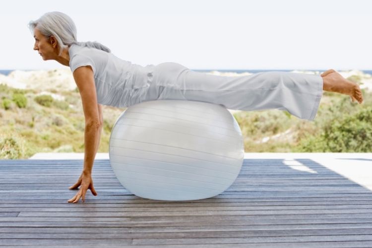 Old woman exercising with an exercise ball outdoor