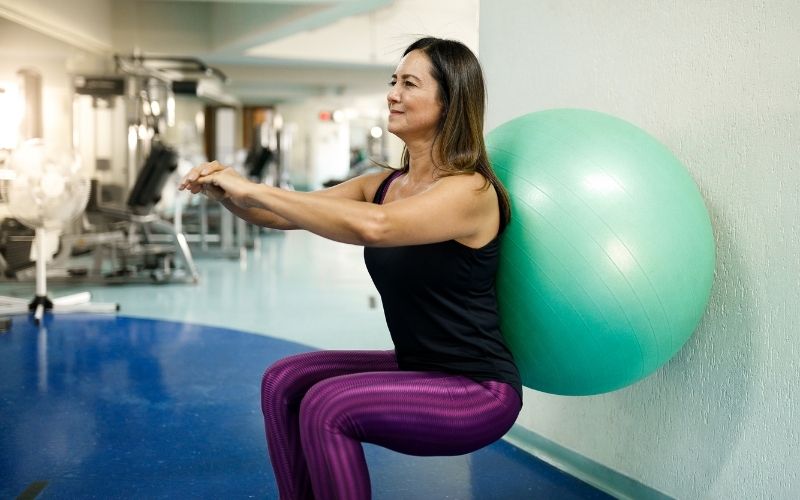 Woman doing wall squat with an exercise ball