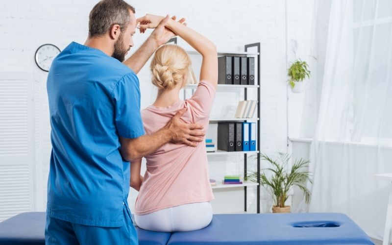 physiotherapist stretching patients arm on massage table in hospital
