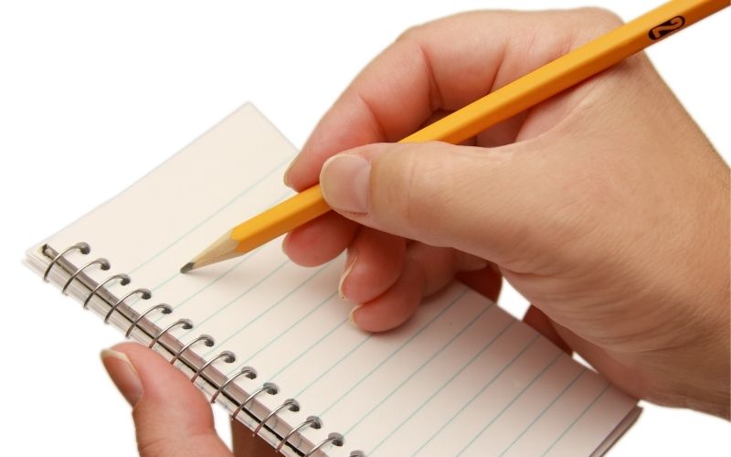 Woman hands holding a pencil and writing on a notebook