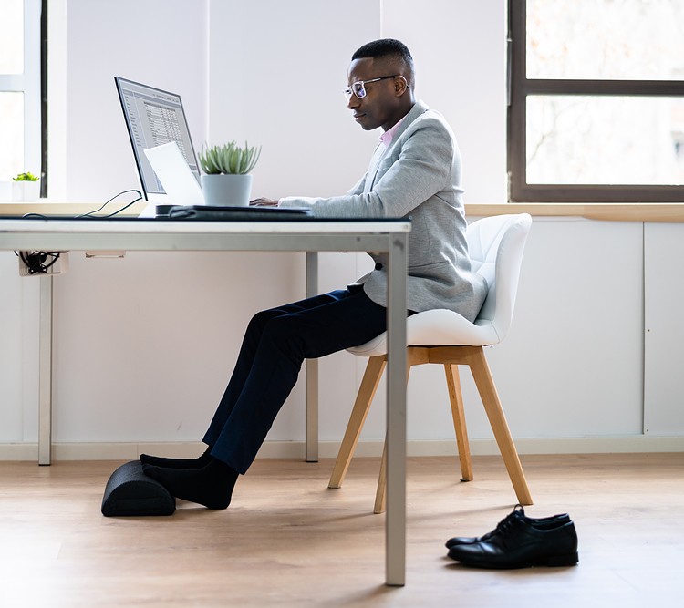 A man using footrest in his office in daylight