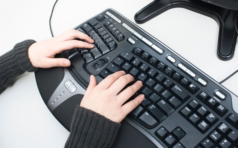 Woman hands typing on ergonomic keyboard