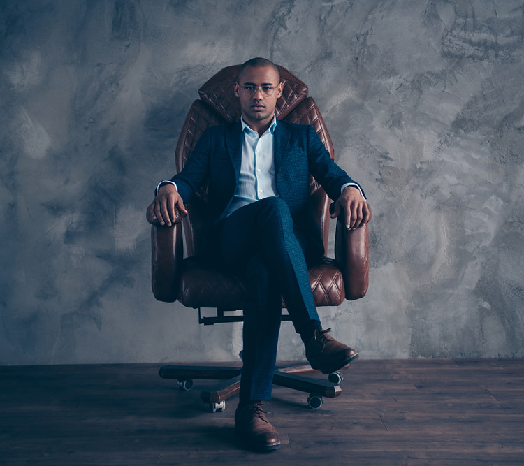 A man sitting cross legged in a grey background