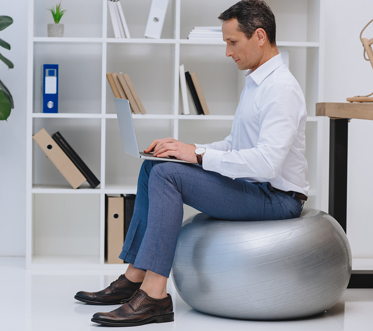 A man using exercise ball as office chair