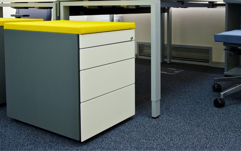 a filing cabinet next to a table in the office